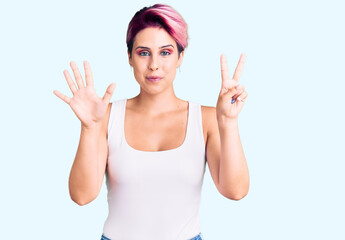 Young beautiful woman with pink hair wearing casual clothes showing and pointing up with fingers number seven while smiling confident and happy.