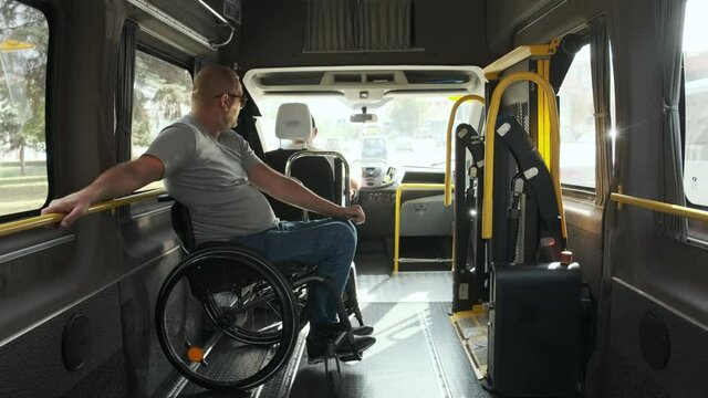 Man in wheelchair in the special the vehicle. The disabled person is transported in a special car. Transportation of disabled people in a special car, bus.