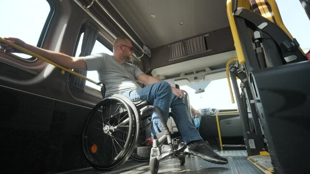 Man in wheelchair in the special the vehicle. The disabled person is transported in a special car. Transportation of disabled people in a special car, bus.