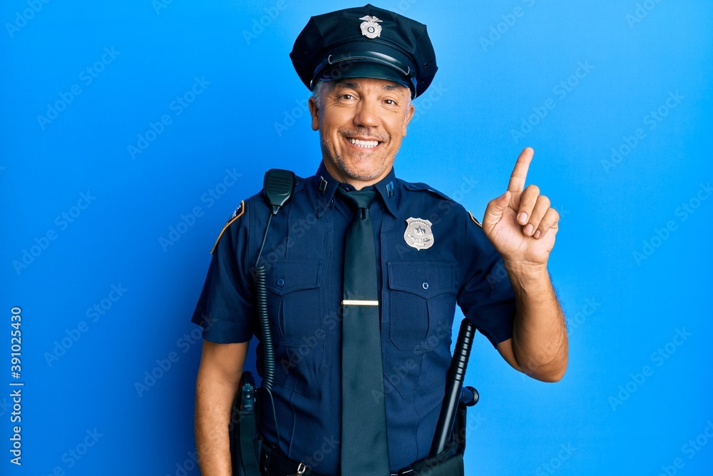 Wall mural handsome middle age mature man wearing police uniform with a big smile on face, pointing with hand f