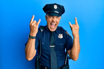 Handsome middle age mature man wearing police uniform shouting with crazy expression doing rock...