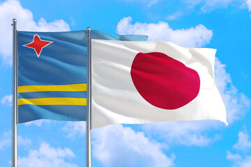 Japan and Aruba national flag waving in the windy deep blue sky. Diplomacy and international relations concept.