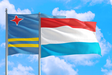 Luxembourg and Aruba national flag waving in the windy deep blue sky. Diplomacy and international relations concept.