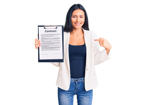 Young beautiful latin girl holding clipboard with contract document pointing finger to one self smiling happy and proud