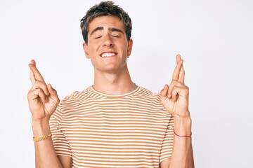 Young handsome man wearing casual clothes gesturing finger crossed smiling with hope and eyes closed. luck and superstitious concept.