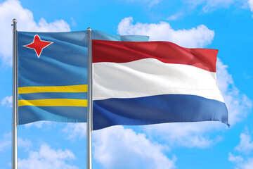 Fototapeta na wymiar Netherlands and Aruba national flag waving in the windy deep blue sky. Diplomacy and international relations concept.