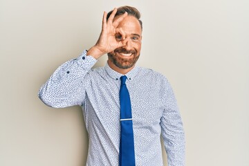 Handsome middle age man wearing business shirt and tie doing ok gesture with hand smiling, eye looking through fingers with happy face.
