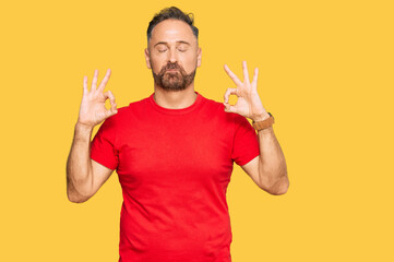 Fototapeta premium Handsome middle age man wearing casual red tshirt relax and smiling with eyes closed doing meditation gesture with fingers. yoga concept.