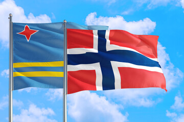 Norway and Aruba national flag waving in the windy deep blue sky. Diplomacy and international relations concept.