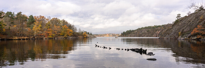 Obraz premium Panorama of Nature Reserve in Sweden. View of the Baltic Sea bay near Stockholm. Rocks cliffs of archipelago. Spruce pine conifers trees grow on granite islands. Scandinavian landscape in autumn.