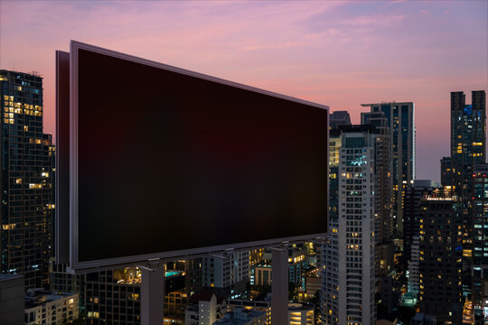 Blank black road billboard with Bangkok cityscape background at night time. Street advertising poster, mock up, 3D rendering. Side view. The concept of marketing communication to promote idea.