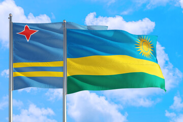 Rwanda and Aruba national flag waving in the windy deep blue sky. Diplomacy and international relations concept.