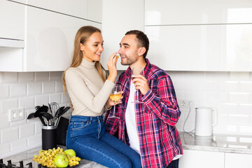 Loving young couple with wine glasses sitting in the kitchen at home