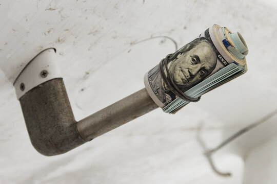 A dollar, a bundle of twisted dollar bills worn on a Pitot tube on the wing of an airplane, close-up, the concept of money as security.