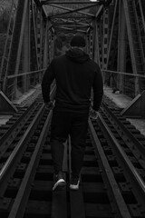 A man walks across a railway bridge