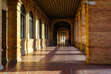 Interior Plaza de España en Sevilla al atardecer en un día soleado, galería que recorre el monumento público.