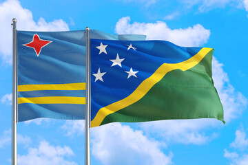 Solomon Islands and Aruba national flag waving in the windy deep blue sky. Diplomacy and...