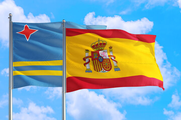 Spain and Aruba national flag waving in the windy deep blue sky. Diplomacy and international relations concept.