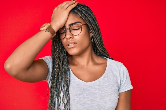 Young african american woman with braids wearing casual clothes and glasses surprised with hand on head for mistake, remember error. forgot, bad memory concept.