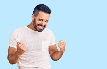 Young hispanic man wearing casual clothes very happy and excited doing winner gesture with arms raised, smiling and screaming for success. celebration concept.