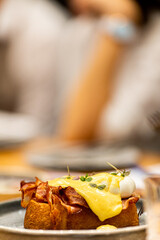 Delicate Egg Benedict sandwich with soft brioche, bacon, poached eggs and Hollandaise sauce