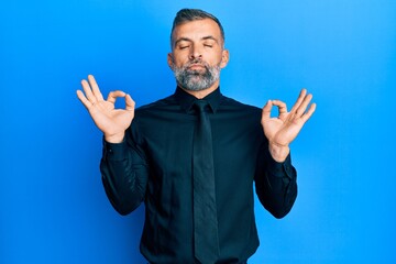 Fototapeta premium Middle age handsome man wearing business shirt and tie relax and smiling with eyes closed doing meditation gesture with fingers. yoga concept.