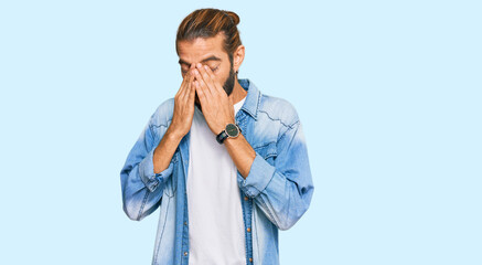 Attractive man with long hair and beard wearing casual denim jacket rubbing eyes for fatigue and headache, sleepy and tired expression. vision problem