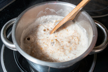 Closeup of oatmeal with milk in a pot cooking on a stove