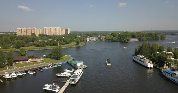 4K high quality calm windless bright summer morning aerial video of Moscow Channel yacht club embankment, green trees, wooden pier and shore with moored anchored boats and yachts near Moscow, Russia