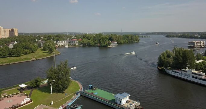 4K high quality calm windless bright summer morning aerial video of Moscow Channel yacht club embankment, green trees, wooden pier and shore with moored anchored boats and yachts near Moscow, Russia