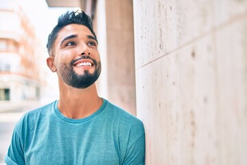 Obraz premium Young arab man smiling happy leaning on the wall at the city.