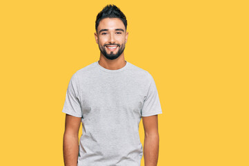 Young man with beard wearing casual grey tshirt with a happy and cool smile on face. lucky person.