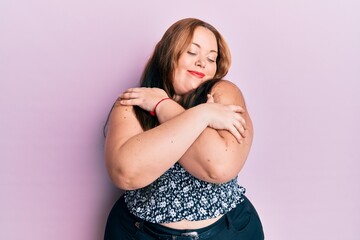 Plus size caucasian young woman wearing casual clothes hugging oneself happy and positive, smiling...