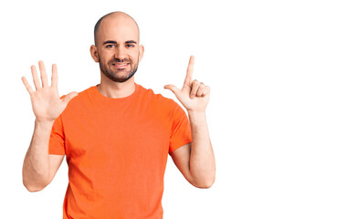 Naklejka premium Young handsome man wering casual t shirt showing and pointing up with fingers number seven while smiling confident and happy.