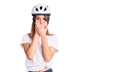 Young beautiful girl wearing bike helmet shocked covering mouth with hands for mistake. secret concept.