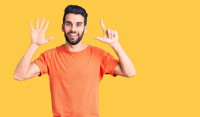 Young handsome man with beard wearing casual t-shirt showing and pointing up with fingers number seven while smiling confident and happy.