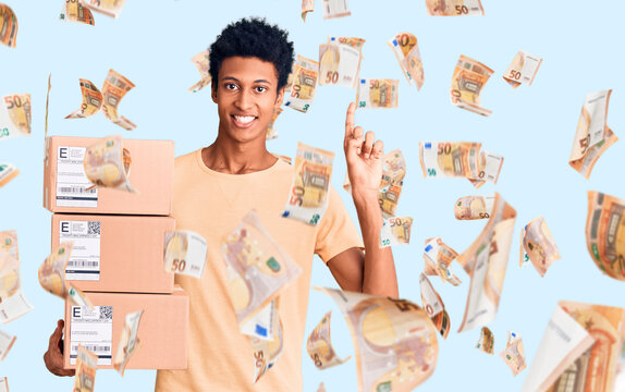 Young african american man holding delivery package surprised with an idea or question pointing finger with happy face, number one