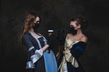 Two women in renaissance dress drinking coffee on abstract dark background