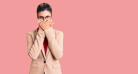 Young beautiful woman wearing business shirt and glasses shocked covering mouth with hands for mistake. secret concept.