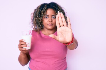 Young african american plus size woman drinking glass of milk with open hand doing stop sign with serious and confident expression, defense gesture