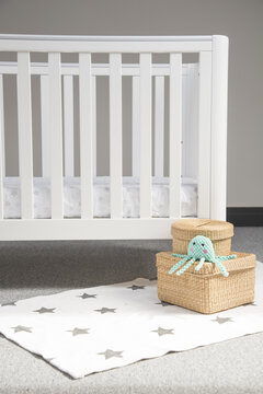 Interior Of Light Baby Room With A Modern Cozy Crib And Woven Wicker Boxes On A Soft Starry Carpet