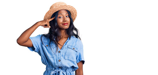 Young indian girl wearing summer hat smiling pointing to head with one finger, great idea or thought, good memory