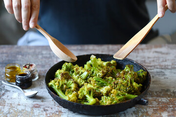 The chef is stirring broccoli in a frying pan. Cooking broccoli. Healthly food.
