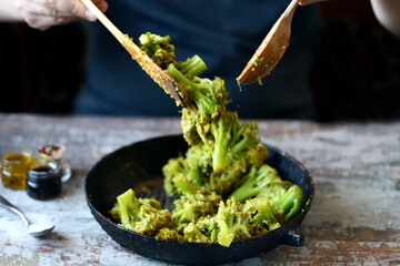 The chef is stirring broccoli in a frying pan. Cooking broccoli. Healthly food. - obrazy, fototapety, plakaty