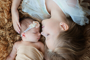 Little Caucasian girl and her newborn sister. Toddler kid meeting new sibling. Cute girl and new born baby relax in a home bedroom. Family with two children at home. Love, trust and tenderness concept