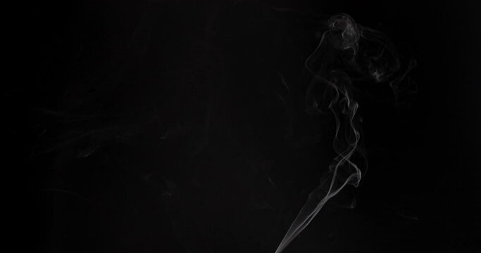 White smoke Ascends Over the Numerous candles. White thin Steam rises from a small candle that is behind the scenes. Isolated on Black background. 4k