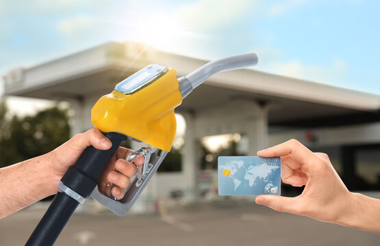 Man holding credit card and worker with fuel nozzle at gas station, closeup. Cashless payment