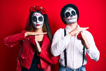 Couple wearing day of the dead costume over red doing time out gesture with hands, frustrated and...