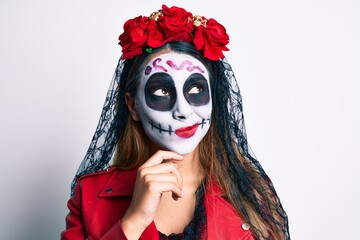 Woman wearing day of the dead costume over white serious face thinking about question with hand on chin, thoughtful about confusing idea