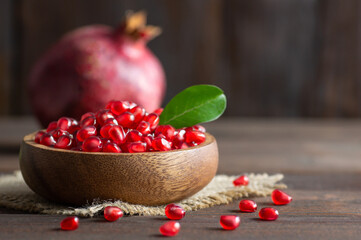 Fresh ripe whole and split  juicy pomegranate with seeds and leaves on wooden rustic background, healthy red fruits concept copy space (Punica granatum)